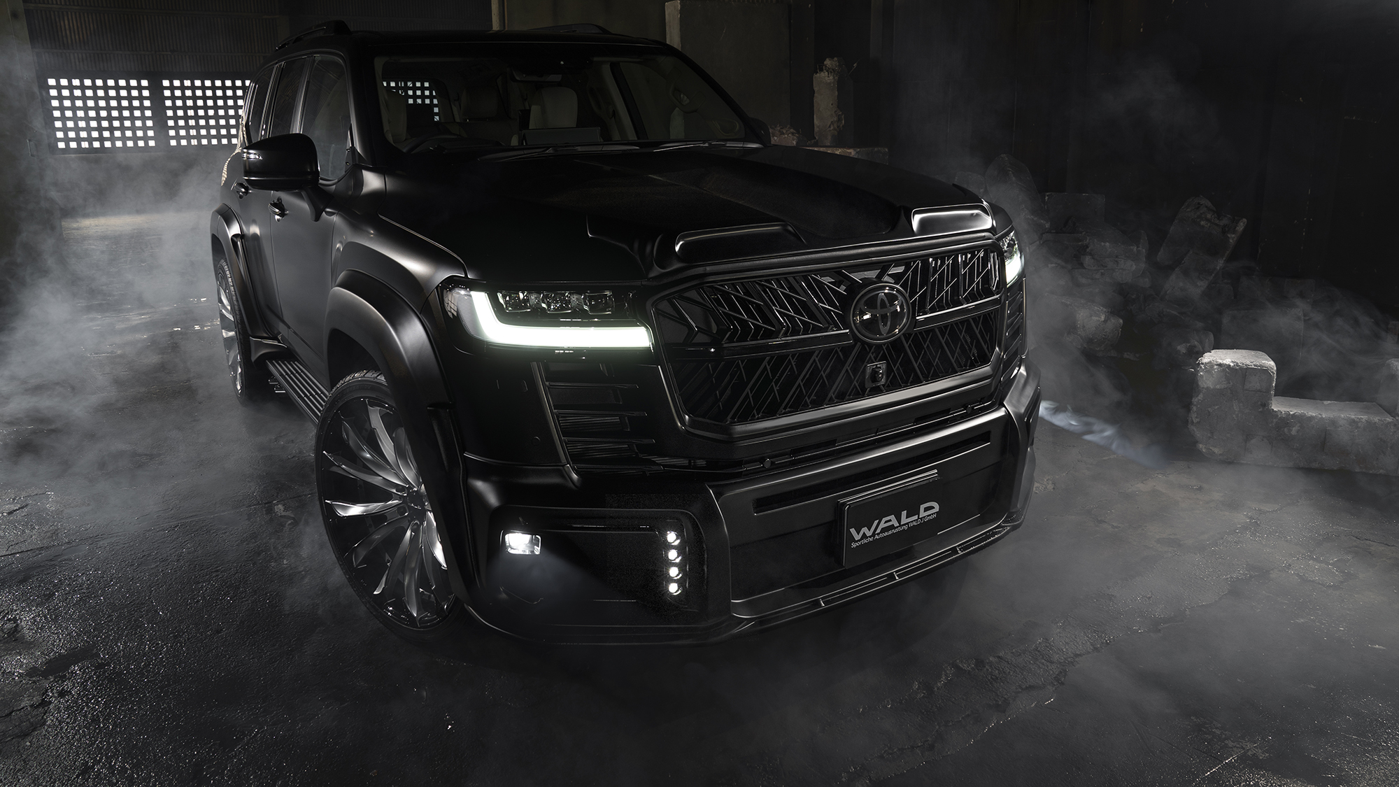 WALD Land Cruiser 300 ZX front three-quarter view with wide arch package and LED headlamps lit