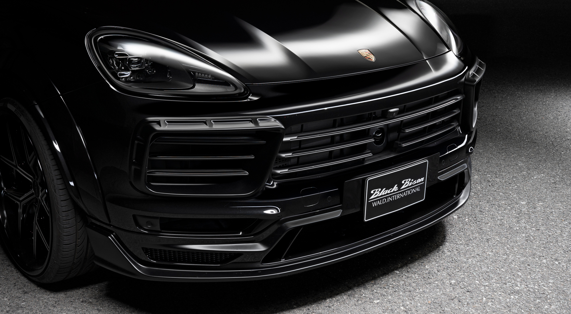 WALD Porsche Cayenne front spoiler detail — Black Bison front spoiler with net and grille close-up