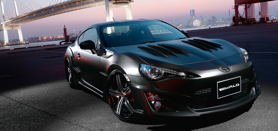 WALD Sports Line Toyota 86 ZN6 body kit — matte black 86 with WALD aero bonnet and front spoiler at Yokohama Bay Bridge