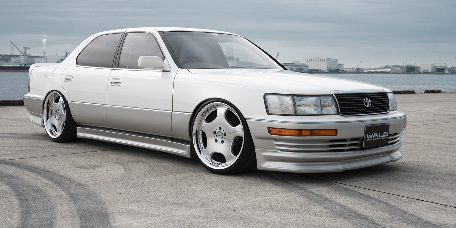 White Toyota Celsior with WALD aero and silver polish Duchatlet II D22C wheels at the dockside